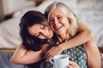 An adult daughter hugs her mother.