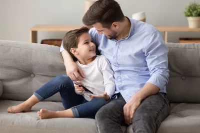 A father talks to his son on the living room couch.