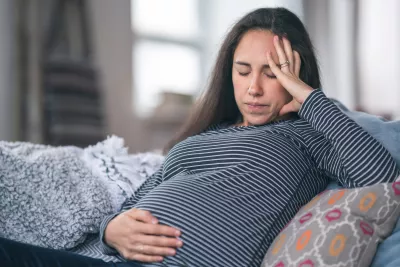 A pregnant woman holds her hand to her stomach.