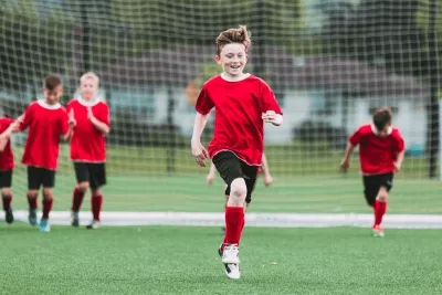 A group of kids in uniforms playing soccer.