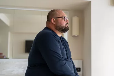 A man sitting at home looking onward.