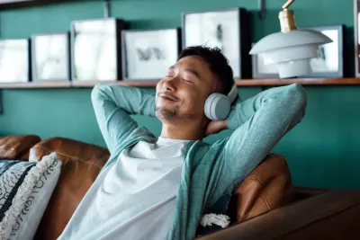 A man relaxing on a couch at home while wearing headphones.