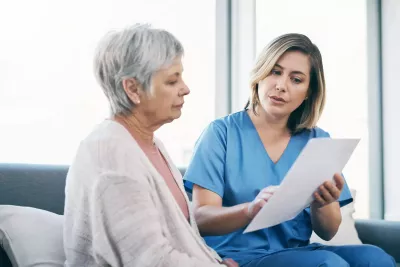 Older female patient looking at a document with her nurse