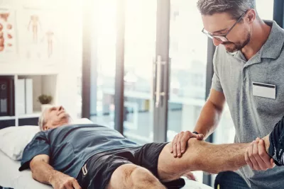 Physical Therapist helping an older male patient with leg.