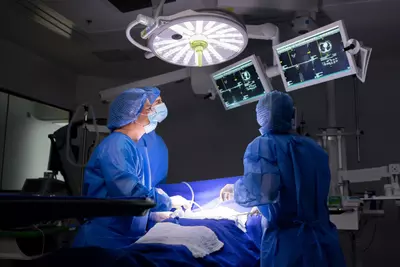 A surgical staff of three people performing a surgery in an operating room.