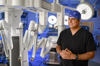 A surgeon standing next to a surgery robot.