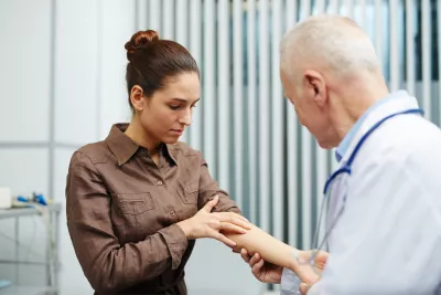 A woman points to arm to show a doctor.