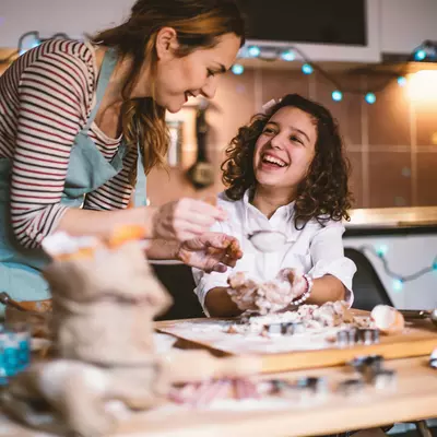 Mother and daughter baking Christmas cookies together in a kitchen.