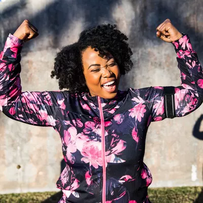 A Woman Triumphantly Flexes Her Arms After a Run in the Park 