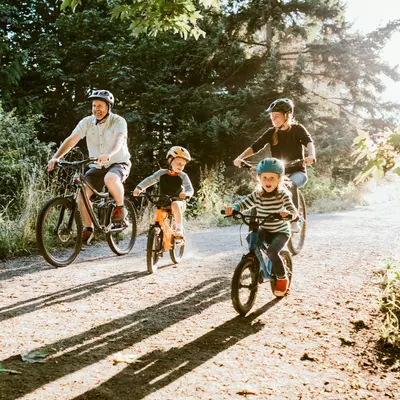 A Family Goes for a Bicycle Ride Through a Park on a Sunny Morning