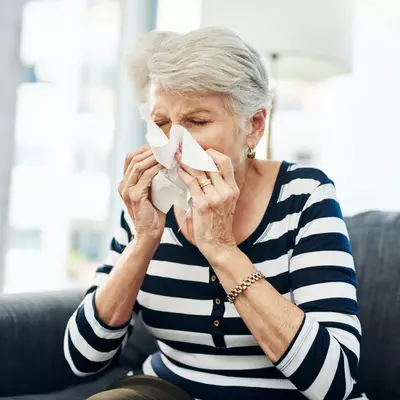 A Senior Woman Blow her Nose with a Tissue