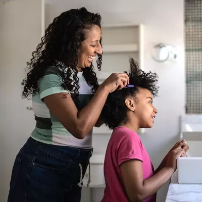 A Mother Helps Her Daughter with Her Hair in The Bathroom.