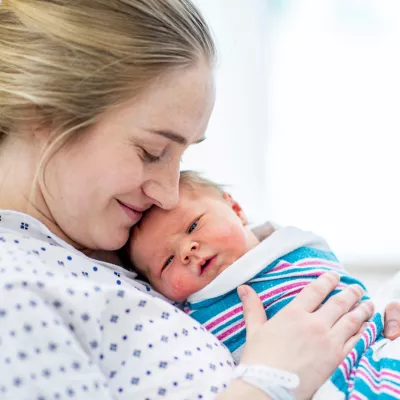 A smiling woman holding her newborn baby.