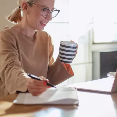 A woman on her computer and taking notes