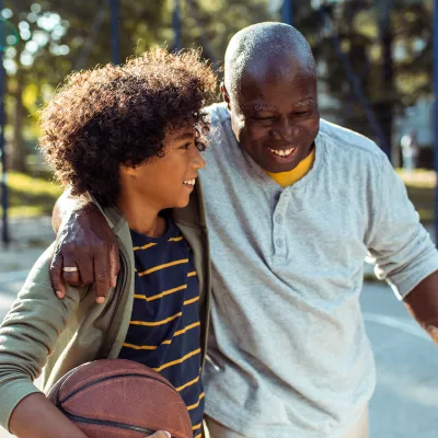 Grandfather and Grandson smiling on a basketball court.
