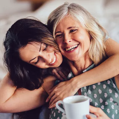 An adult daughter hugs her mother.