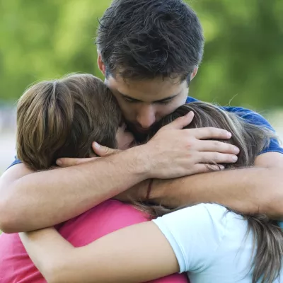 A father hugs his two children.