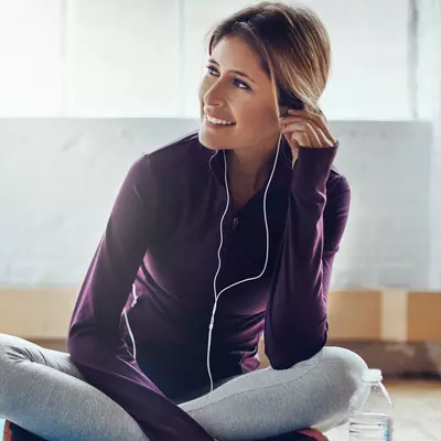 A woman wearing headphones and exercise clothes.