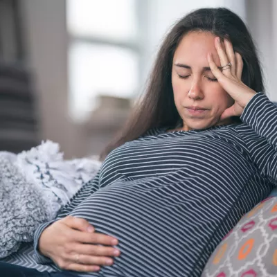 A pregnant woman holds her hand to her stomach.