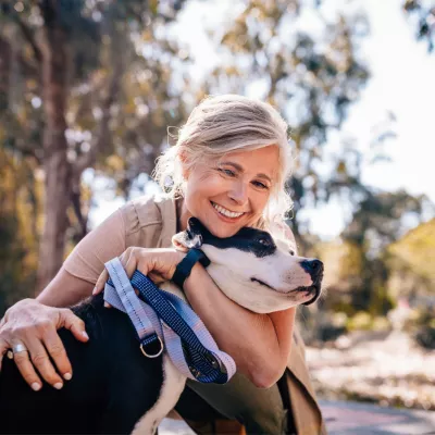 A middle aged woman hugging a dog.