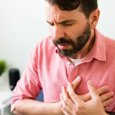 A main sitting and placing hands over chest in pain.