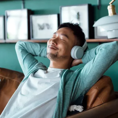 A man relaxing on a couch at home while wearing headphones.