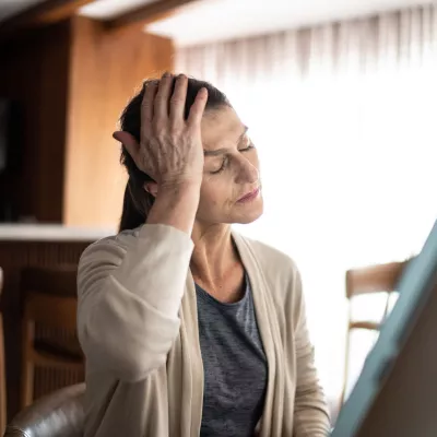 An older woman holding her hand to her head.