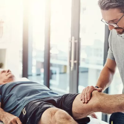 Physical Therapist helping an older male patient with leg.