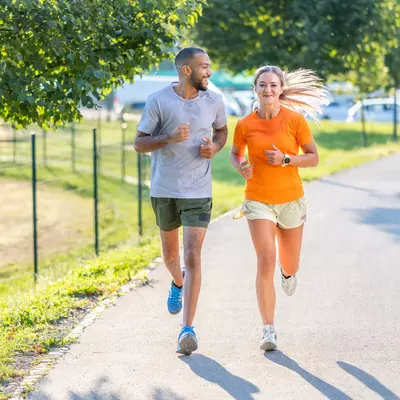 A man and woman running outdoors on a sunny day