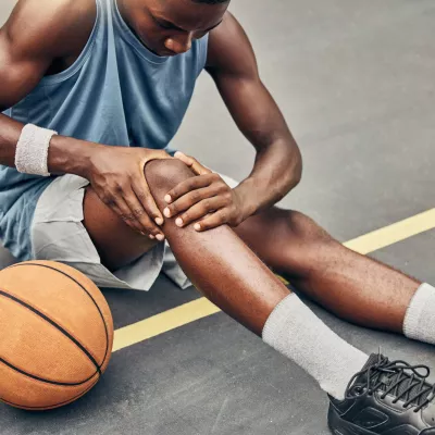 Young male athlete examining his injured knee.