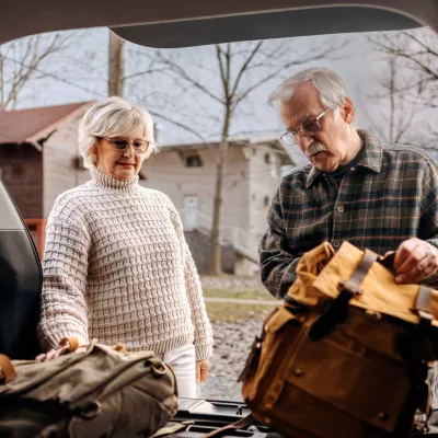 A senior couple packs their car to prepare for a hurricane.
