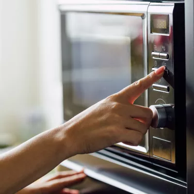 A woman pressing a button of a microwave.