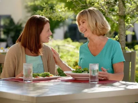 Two women sitting at outdoor table talking and eating