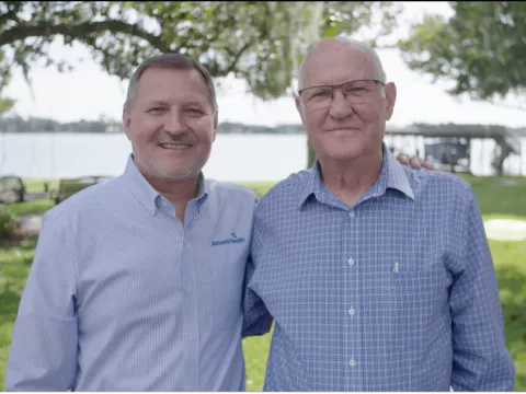 A photo of AdventHealth CEO Terry Shaw and his father standing outside in front of a lake.