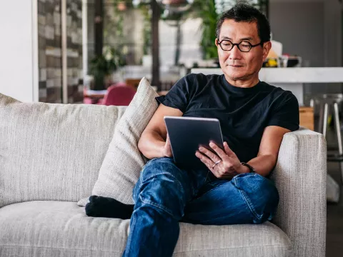 A man reading on his tablet at home.