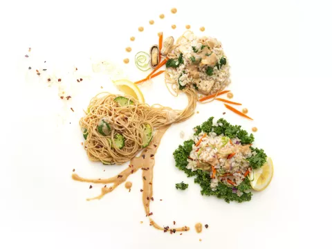 Three mounds of Asian noodles with green garnishes 