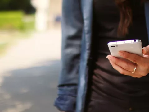 A woman standing while holding a cell phone.