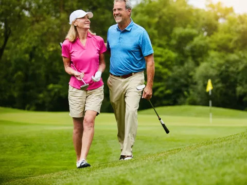 A senior couple, walking on a golf course.