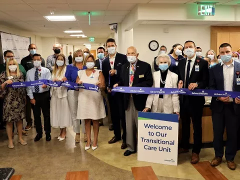 : Accompanied by hospital staff and members of the community, AdventHealth DeLand CEO David Weis cuts the ribbon on the campus’s new Transitional Care Unit.