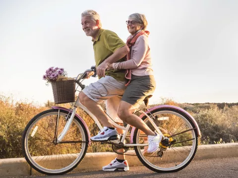 A couple rides a bike together.