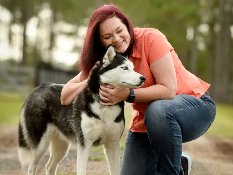 Woman petting her dog while outdoors.