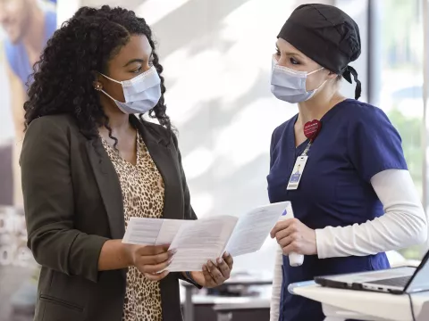 An AdventHealth employee assisting a patient with medical information