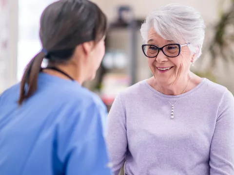 An elderly woman talking to a nurse.