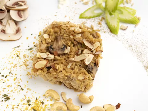 Square of almond chick'n rice on white surface with mushroom decoration