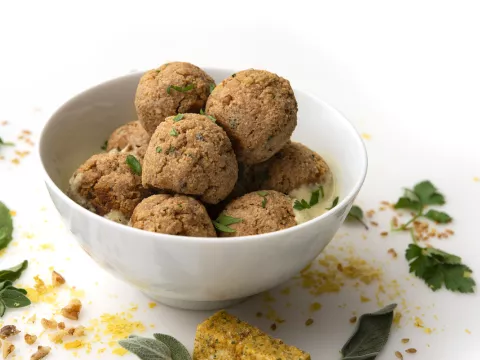 White bowl of no-meat balls with leaf garnishes on white counter