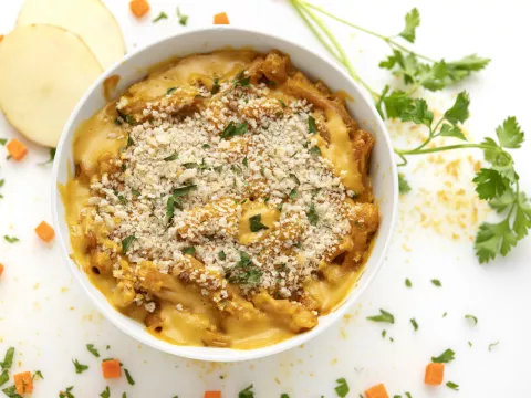 Bowl of mac and cheese with potato and parsley garnish