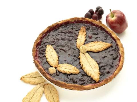 Whole cherry pie with apple, grapes, and leaf-piecrust garnishes