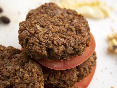 Three black bean burgers patties stacked with tomato slices