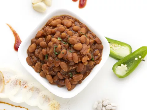 White bowl of baked beans with jalapeño garnish.