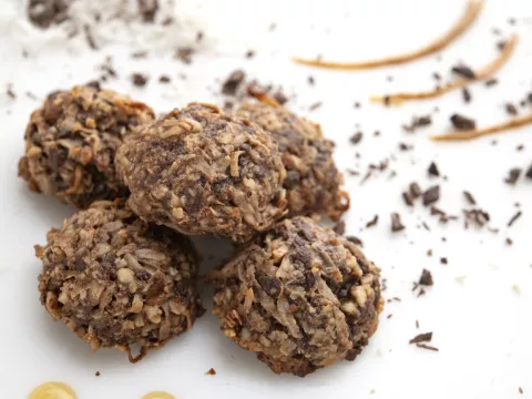 Five coconut mound cookies on a white surface